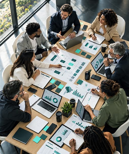 Equipe reunida em volta de uma mesa com dashboards, fluxogramas e indicadores comerciais.